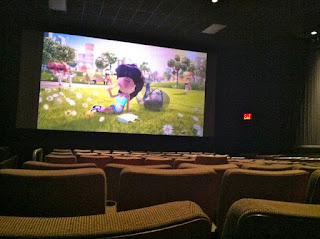 photo of a movie being shown at a movie theater. There are empty seats everywhere.