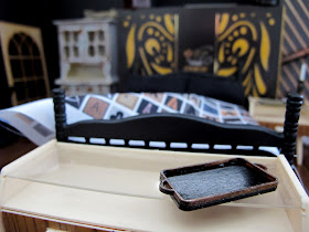 Modern dolls' house miniature room set up in dark shades of black, brown and cream.