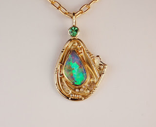 yellow gold pendant with a tear drop shaped multicolor opal and green stone