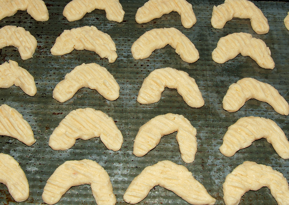 Almond crescent cookies placed on a baking tray, ready to go into the oven.