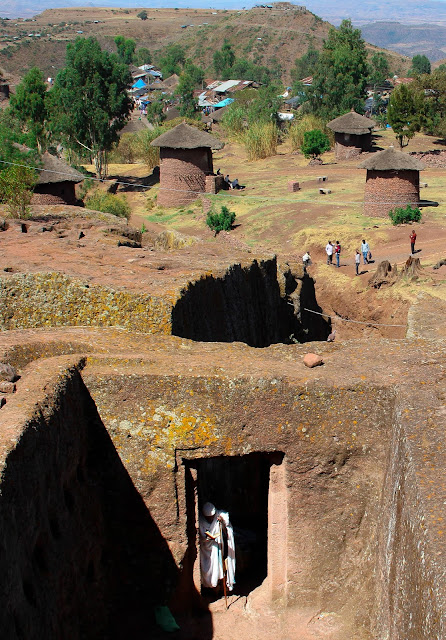 tukuls and churches in Lalibela. a man praying in the doorway of a church tunnel
