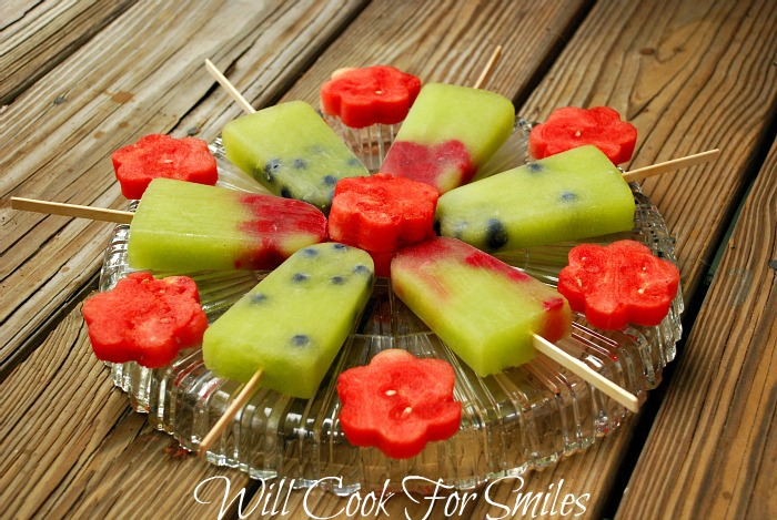 Honeydew Melon Berry ice Pops with watermelon flowers between them on a glass platter on a picnic table 