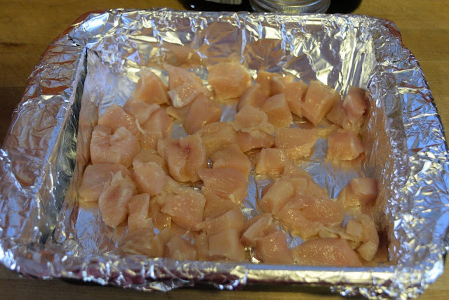 The pieces of raw chicken, cubed, and placed in a foil lined baking dish.
