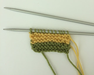 The start of a hand knitted yellow and green scarf