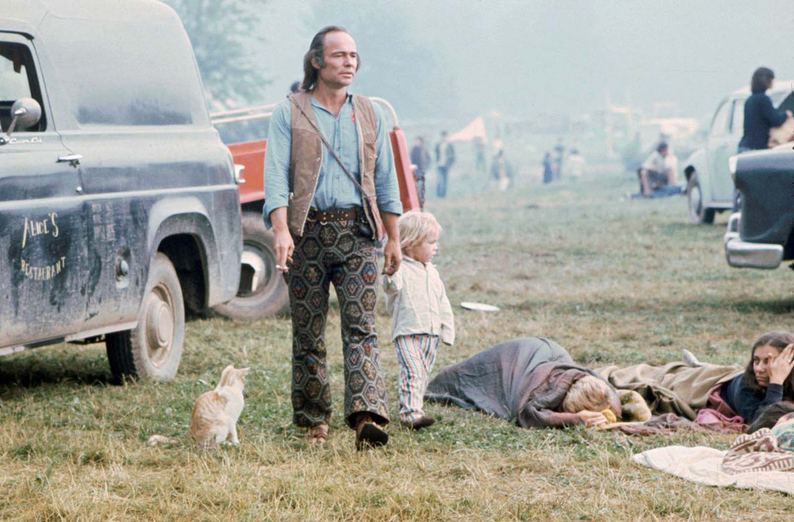 A man and a child walk past people in sleeping bags in August 1969.