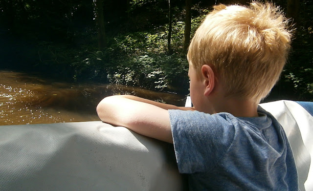 young boy looking out over water on canal boat