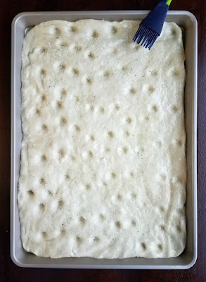 dough with dimples being brushed with oil