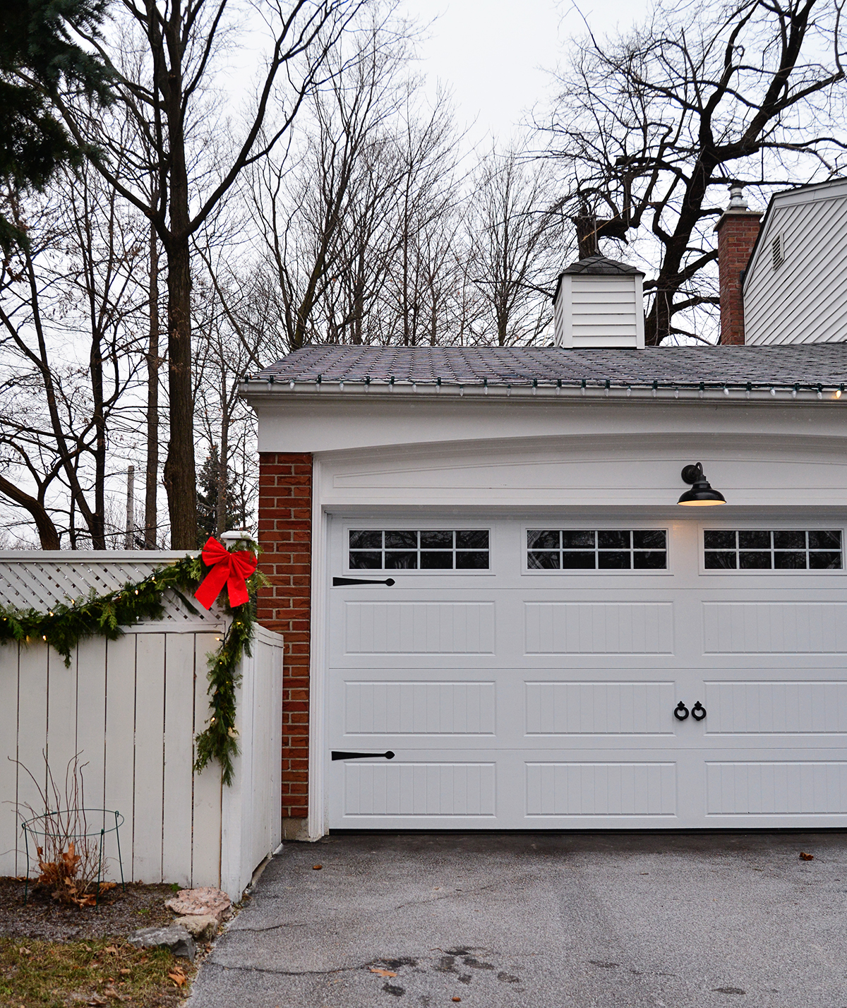 Christmas colonial house with garland on white fence