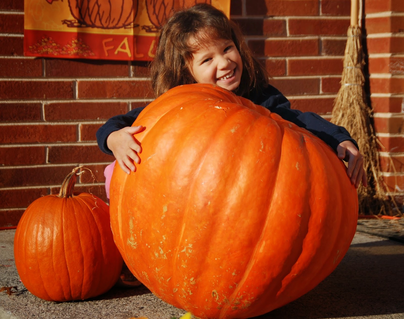 Girl posing with a large pumpkin for Halloween