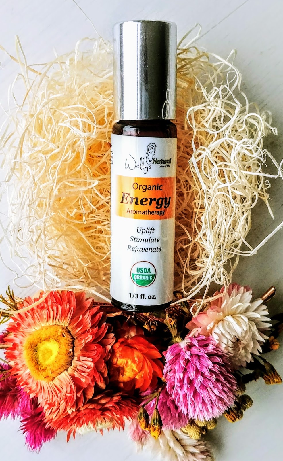An organic energy aromatherapy rollerball by Wally's Natural on a flower scene