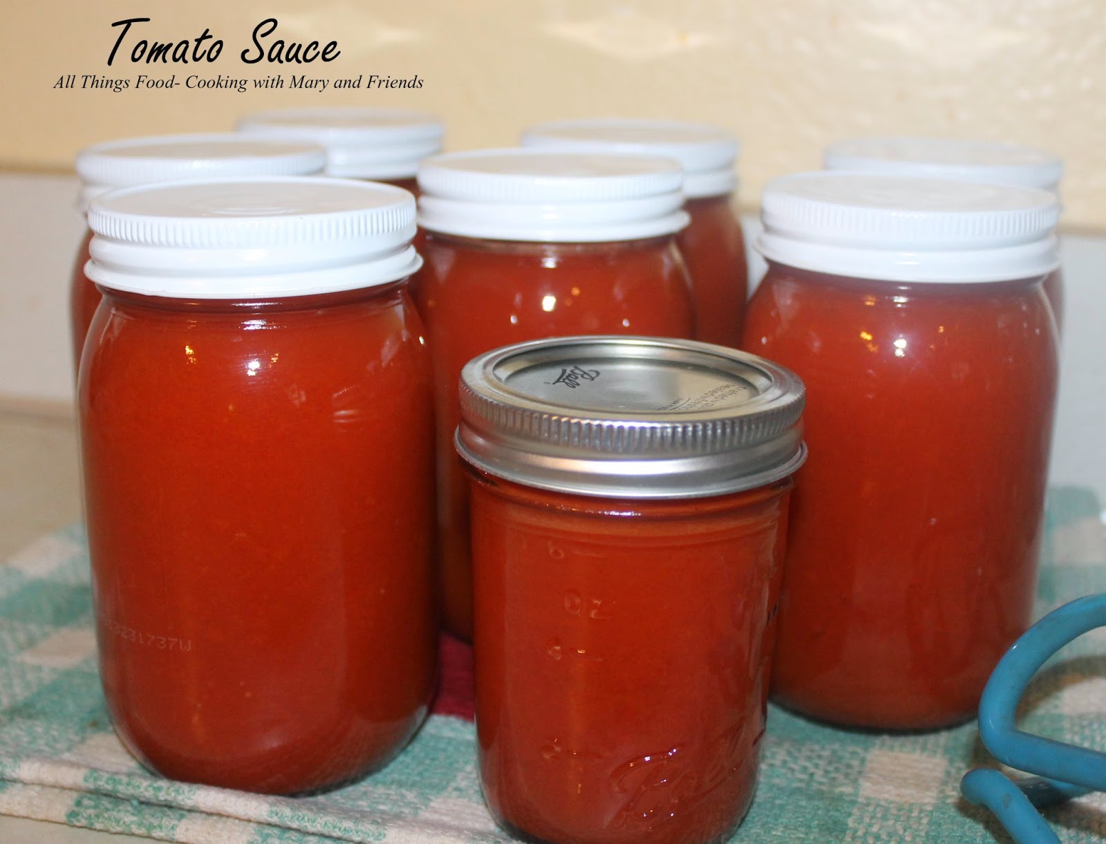 A glass jar filled with rich, red homemade tomato sauce surrounded by fresh herbs and garlic.