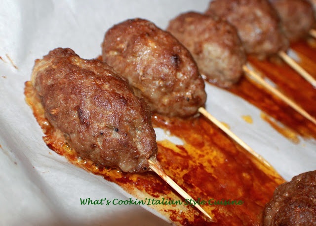 baked sausage skewers on a stick on a cookie sheet