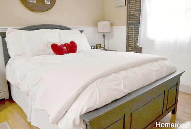Bed with white comforter and red heart pillows