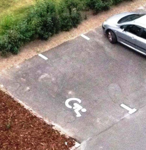 En una plaça d'aparcament reservada a persones amb discapacitat, han pintat el logo amb els elements en ordre incorrecte.
