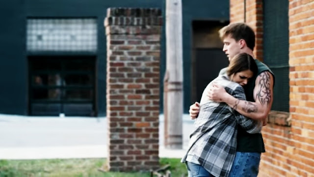 Um casal de jovens se abraçam, no braço do homem tem uma tatuagem imagem do filme Uma Vida Com Propósito