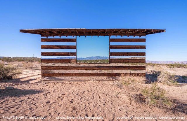 Cabaña transparente de madera y espejos en un paisaje desértico