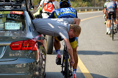 A staff of team Saxo Tinkoff repairs the bicycle for a cyclist as they ride through a country road during the first stage of the 2013 Tour of Beijing cycling race