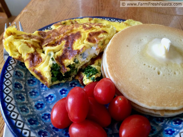 image of a plate of garlic scape and goat cheese omelette with grape tomatoes and pancakes