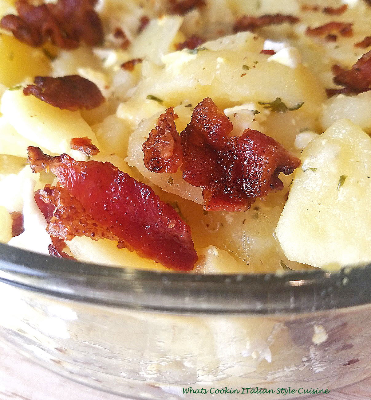 this is a cheese, bacon, sour cream potato casserole in a glass see through bowl