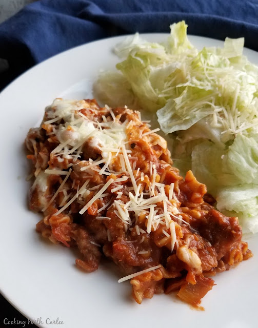 All of the flavors of lasagna cooked in one skillet on the stove. One pot skillet lasagna makes it possible to get it done on a weeknight and without a ton of dishes! serving of skillet lasagna with shredded parmesan and salad on a plate