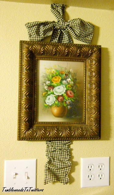 framed floral oil painting with checkered ribbon bow and tail