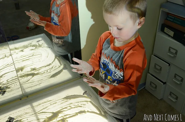 Preschool child looking at hands after some messy sensory play on the light table