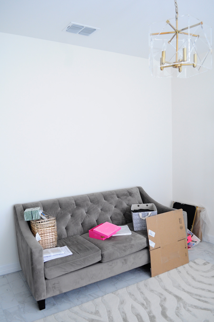 A tufted sofa serves as a daybed in a home office makeover. Tufted Chloe sofa along a white wall.