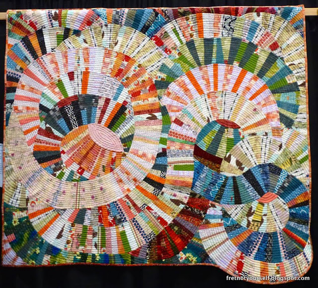 Improv Curve quilt using prints in pink, coral, white, blue, green and red