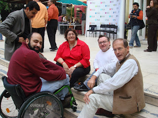 Simon sitting on some conrete steps, with an Egyptian man wheelchair user and two other people