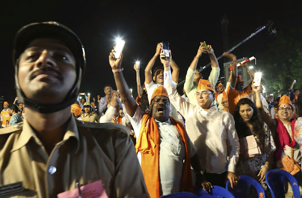 Supporters of the Bharatiya Janata Party hold their cellphones and shout slogans