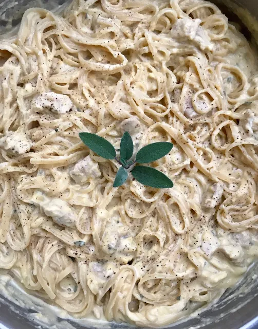 Pan of pumpkin alfredo pasta with chicken topped with fresh sage.