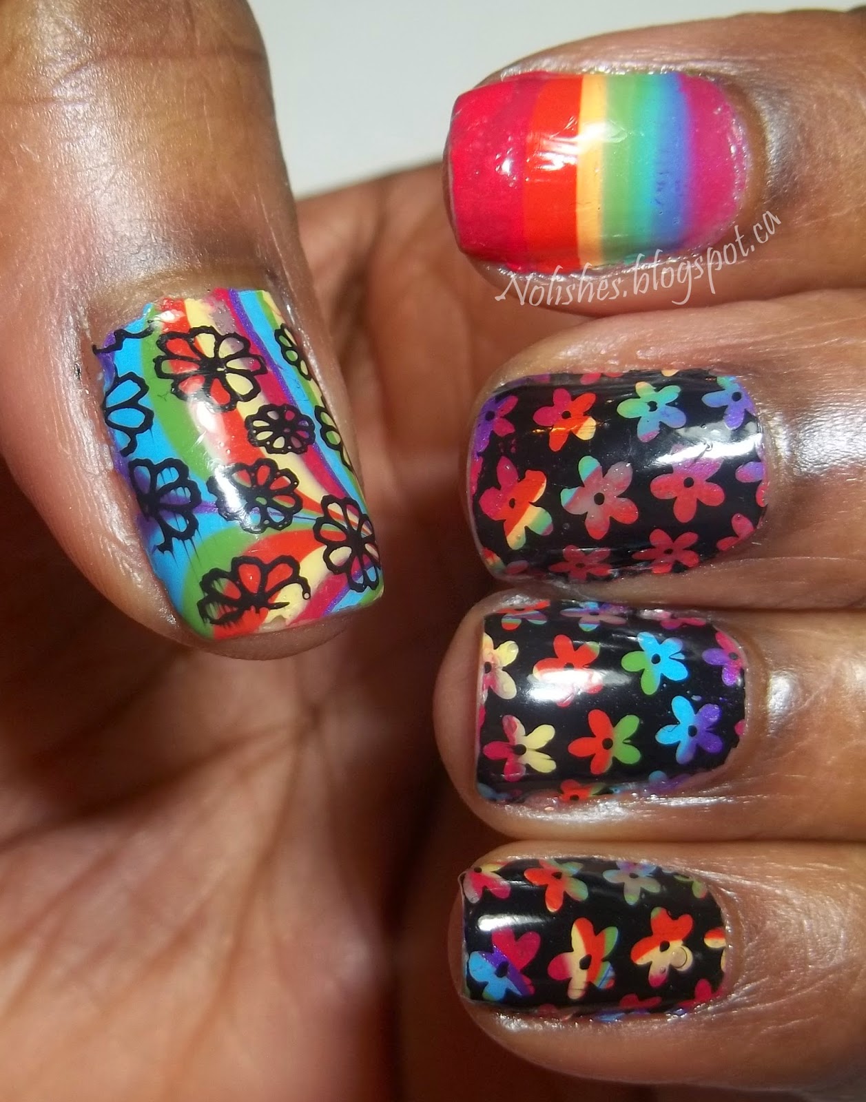 Nail stamping manicure featuring a rainbow coloured water marble base stamped with flower images in black. An index finger accent nail is left unstamped, and features bands of the colours of the rainbow.