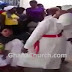 Church members look on as leader throws little girl around