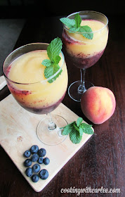 What a perfect way to cool off! These delicious peach and blueberry wine slushies are pretty, refreshing and only take a few ingredients and a couple of minutes to make! looking down at wine glasses with layers of peach and blueberry wine slush