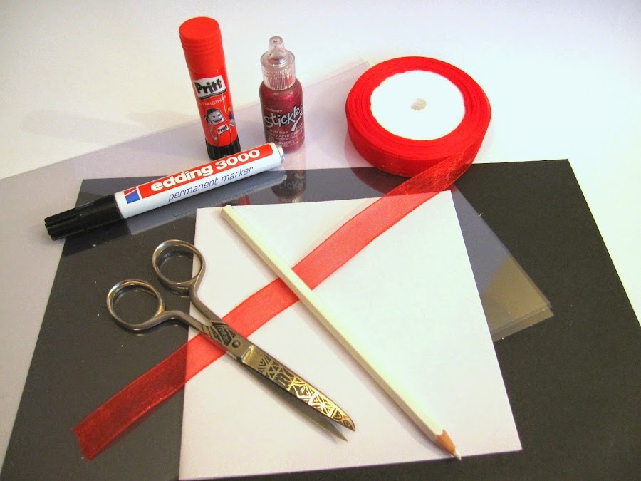 material para hacer tarjeta scrapbooking San Valentin Luna Roja: tarjeta, cinta gasa roja, lazo rojo, cartulina negra, plástico transparente, rotulador permanente, lápiz blanco, pegamento Pritt, stickles cramberry