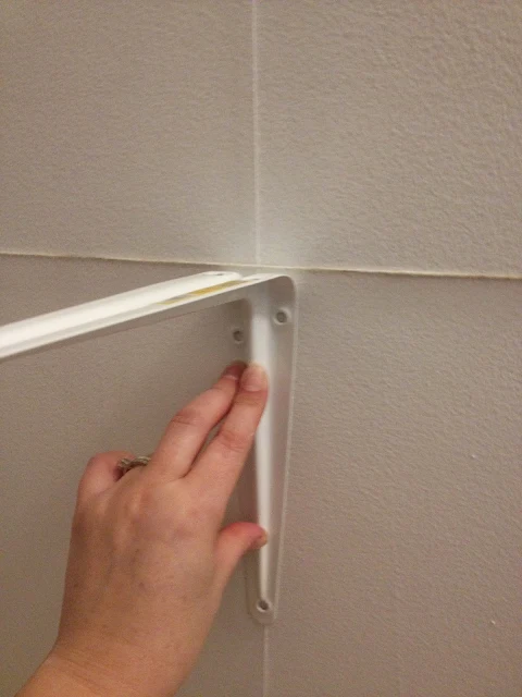 aligning shelf bracket on wall