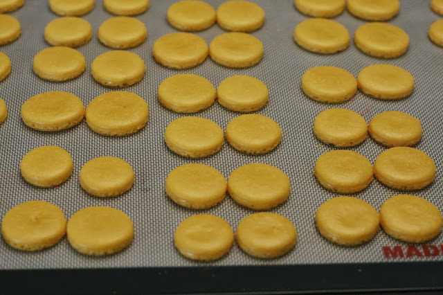 Pairs of baked macaron shells on a baking sheet that are matched according to size