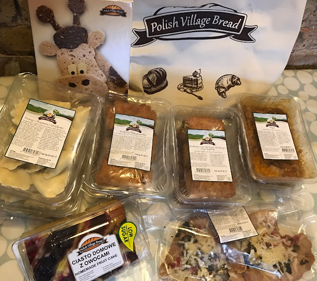 Lots of plastic boxes with preprepared polish food in, in front of a bag saying Polish Village Bakery and a jigsaw of a giraffe made from bread
