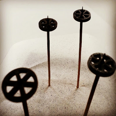 Wheels from a one-twelfth industrial trolley kit mounted on skewers and painted black and rusty shades.