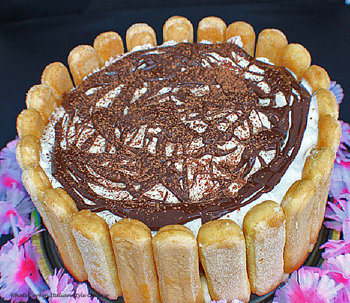 This is an eggless tiramisu with lady fingers, sponge cake a no bake filling topped with whipped cream, hot fudge and dusted with unsweetened cocoa powder