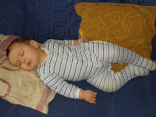 Baby Boy asleep on the sofa holding a spoon