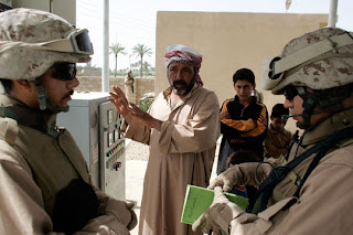 A Marine officer talks through an Iraqi interpreter (L), with the manager of a water pump project near Fallujah. (Joe Raedle/Getty Images)