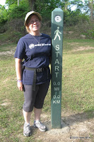 Judi stands next to the first of five mileage posts.