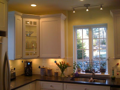 Kitchen after remodeling with recycled glass backsplash, cabinets with glass door and shelves, under cabinet lighting and a halogen light track