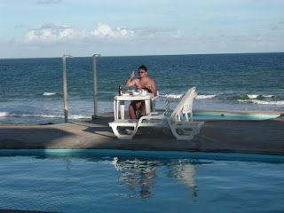 Piscina e pessoa comendo na mesa em frente à praia de Arembepe