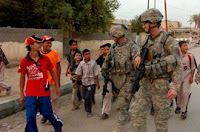 Staff Sergeant Brian Doty (left), of Orange, Va. and Cpl. Sam Weaver, of Fayetteville, N.C., both with Company B, 13th Psychological Operations Battalion, are accompanied by local children while on a foot patrol in the city of Suwayrah in northern Wasit province. Photo by Sgt. David Turner.