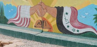 A painting depicting partnership between the United States and Iraq sits outside the gate leading to the Bucca Enrichment School at Camp Bucca's theater internment facility. The school teaches detainees valuable argriculture skills, as well as affords them the chance to paint, draw and do carpentry work. Final products are displayed throughout the TIF and other military compounds, and are used by the detainees themselves for entertainment purposes.