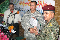 Army Capt. Steven Kendall presents a partnership certificate to Iraqi Army Lt. Col. Hillal at a ceremony to mark what Iraqis are calling National Sovereignty Day in Majaar Al Kabir, Iraq, June 30, 2009. Following the ceremony, Kendall's unit vacated its combat outpost at a defunct sugar factory while Iraqi soldiers moved in.