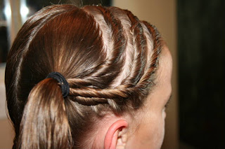 Side view of Young girl's hair being styled into "Triple Twists and Messy Buns"