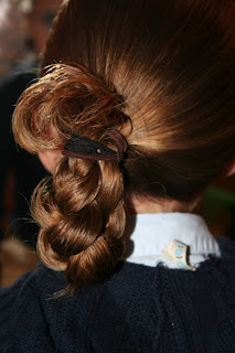 Back view of young girl's hair being styled into "Ponytail Half Braid"